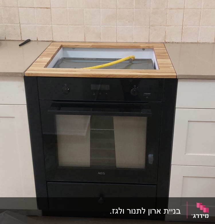 תנור שחור מותקן במטבח עם צינור גז צהוב